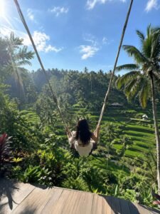 Candid mobile photo of a traveler enjoying the Ubud Jungle Swing overlooking green rice terraces in Bali Indonesia