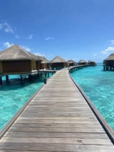 wooden jetty walking toward overwater villas in the Maldives with turquoise lagoon water