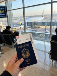 First-person mobile photo of a UAE passport held at Dubai International Airport departure gate before boarding a flight to a visa on arrival country